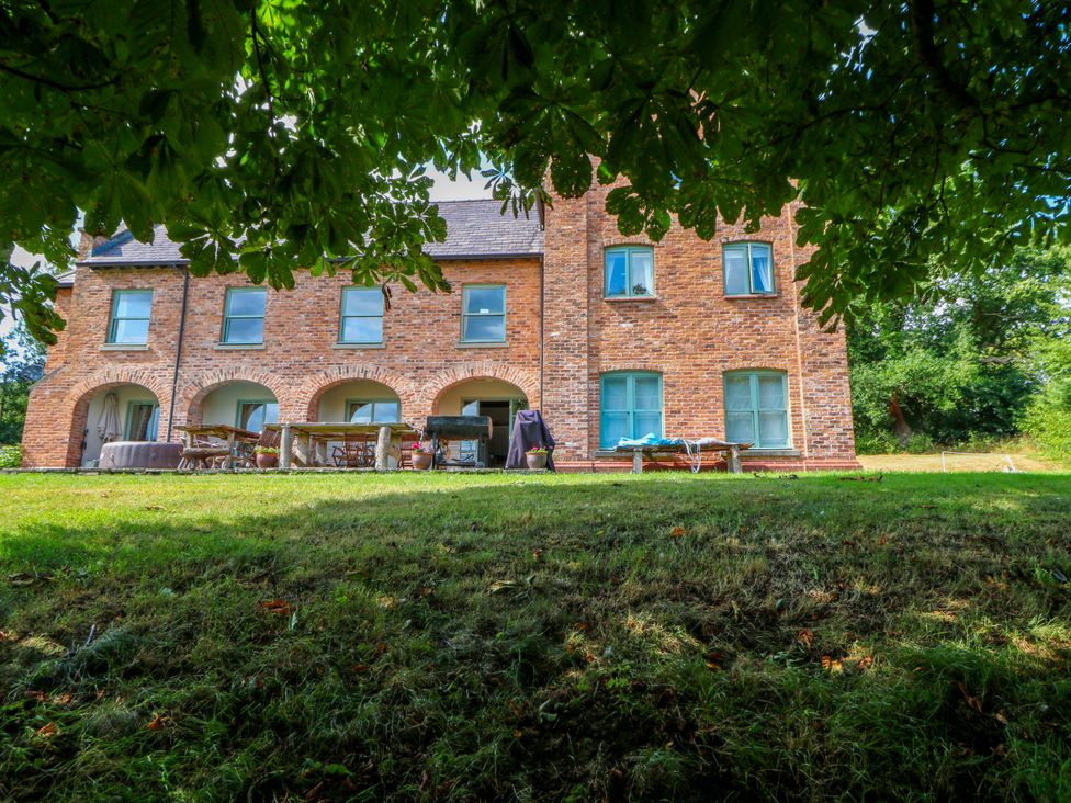 A brick building with windows and outdoor furniture at Gaer Hall Welshpool