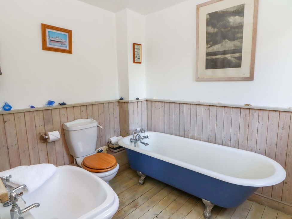 A bathroom with a bath tub, toilet, and sink at Gaer Hall in Welshpool