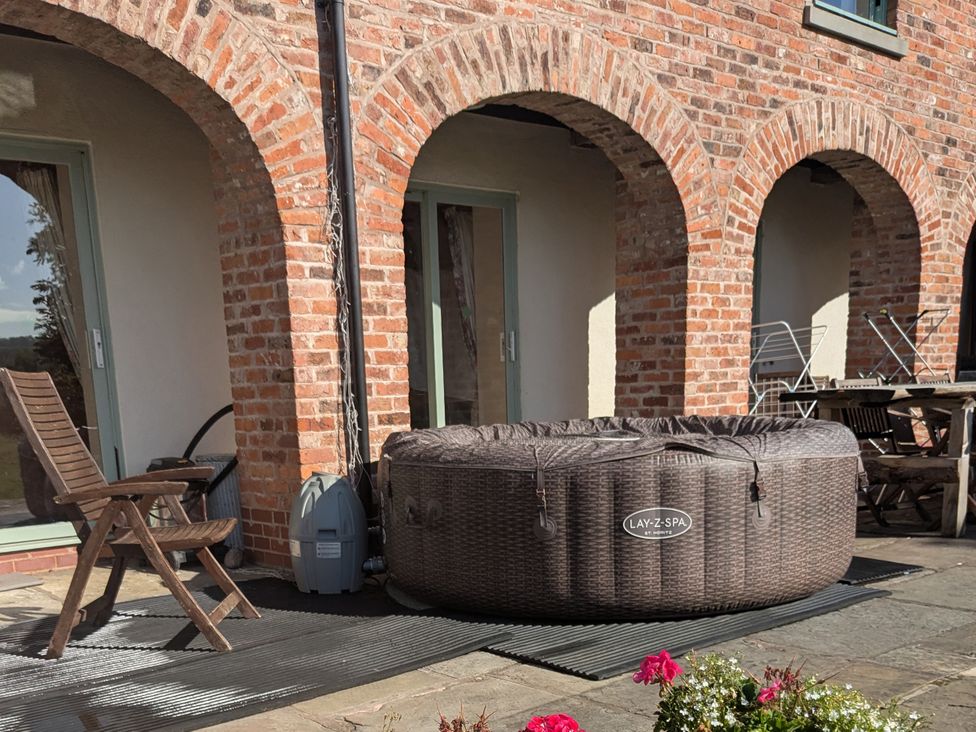 An outdoor area with a hot tub and a deck chair at Gaer Hall in Guilsfield