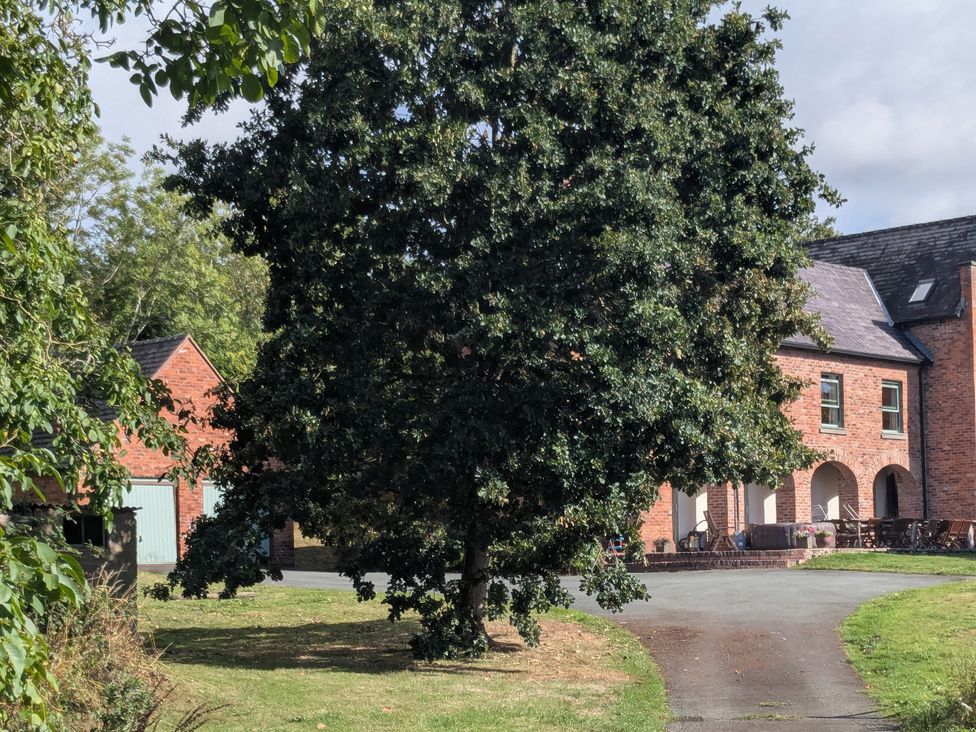 A house with a large tree and outbuilding at Gaer Hall Guilsfield