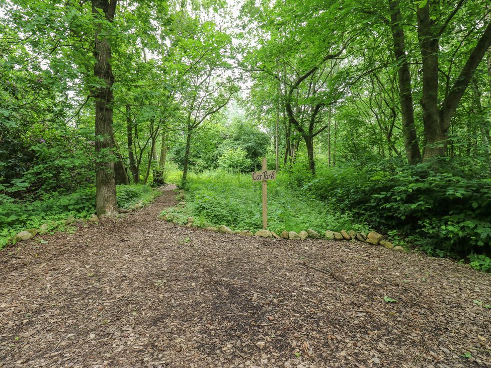 A pathway leading to a car park sign in a wooded area at The Leveret Eppleby