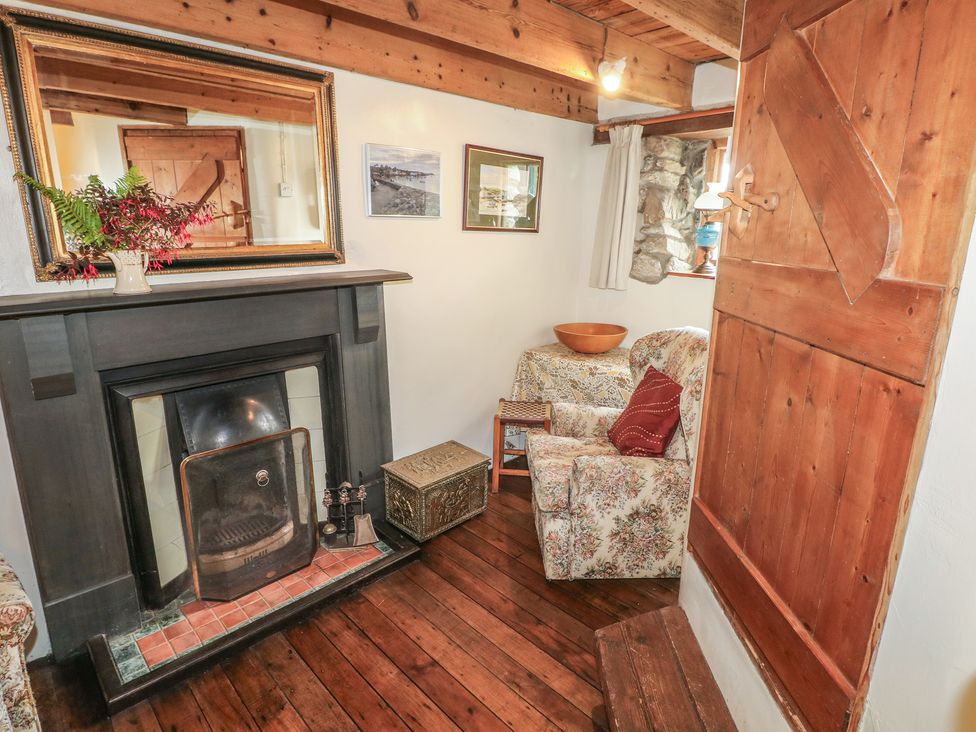 A snug with a fireplace and an armchair at Penfeidr Newydd in Carningli Common, Newport, Pembrokeshire