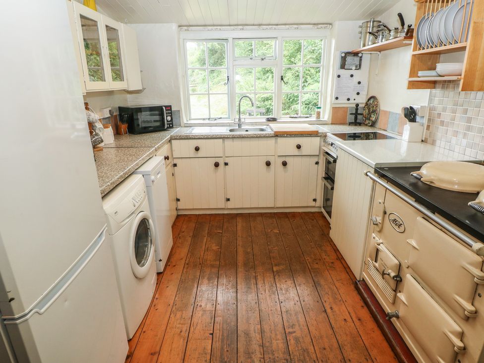 A kitchen with various appliances and wooden flooring at Penfeidr Newydd, Carningli Common, Newport, Pembrokeshire