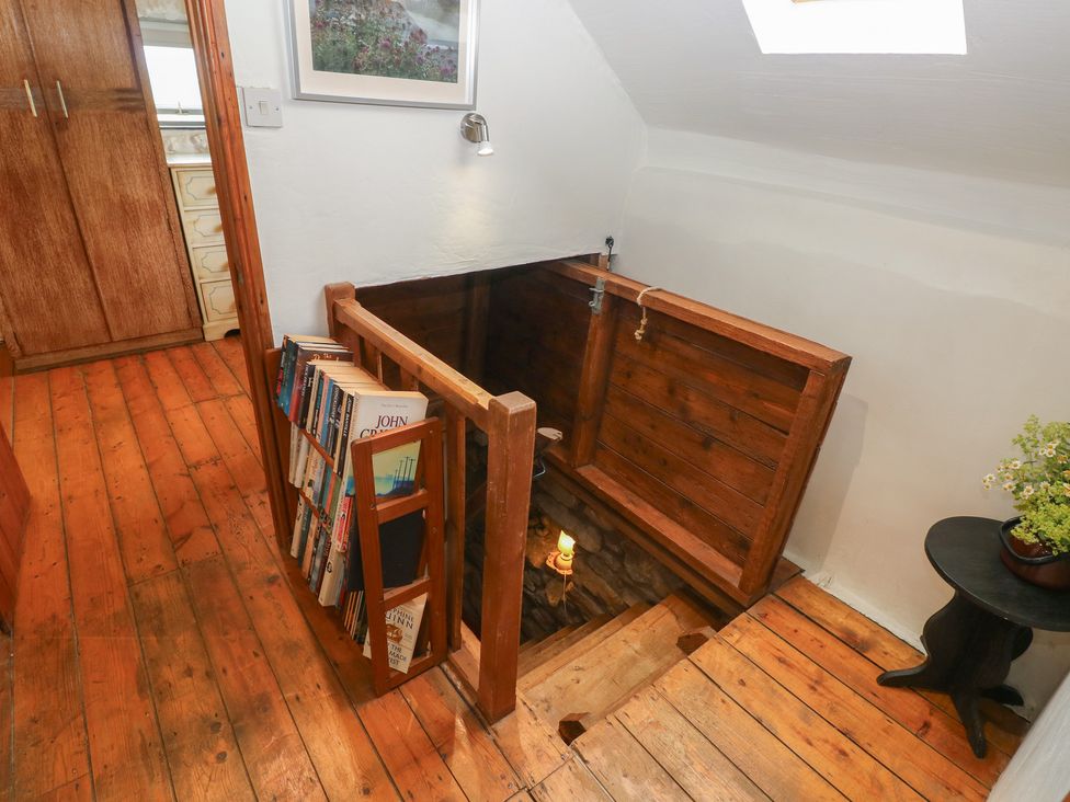 A landing with wooden stairs and bookshelf at Penfeidr Newydd, Carningli Common, Newport, Pembrokeshire