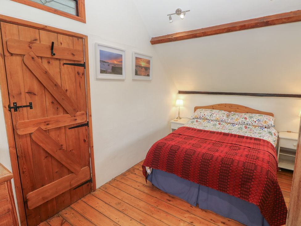 A bedroom with a bed and wooden door at Penfeidr Newydd, Carningli Common, Newport, Pembrokeshire
