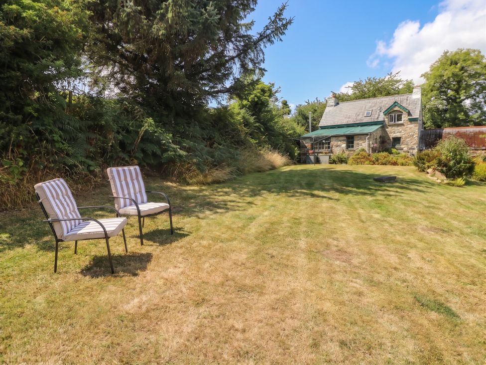 A garden with two chairs and a house in the background at Penfeidr Newydd, Carningli Common, Newport, Pembrokeshire