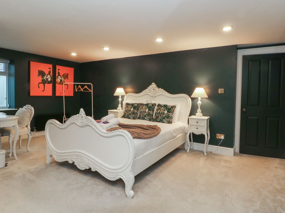 A bedroom with a large bed and decorative paintings at Alexander in Cabus near Garstang