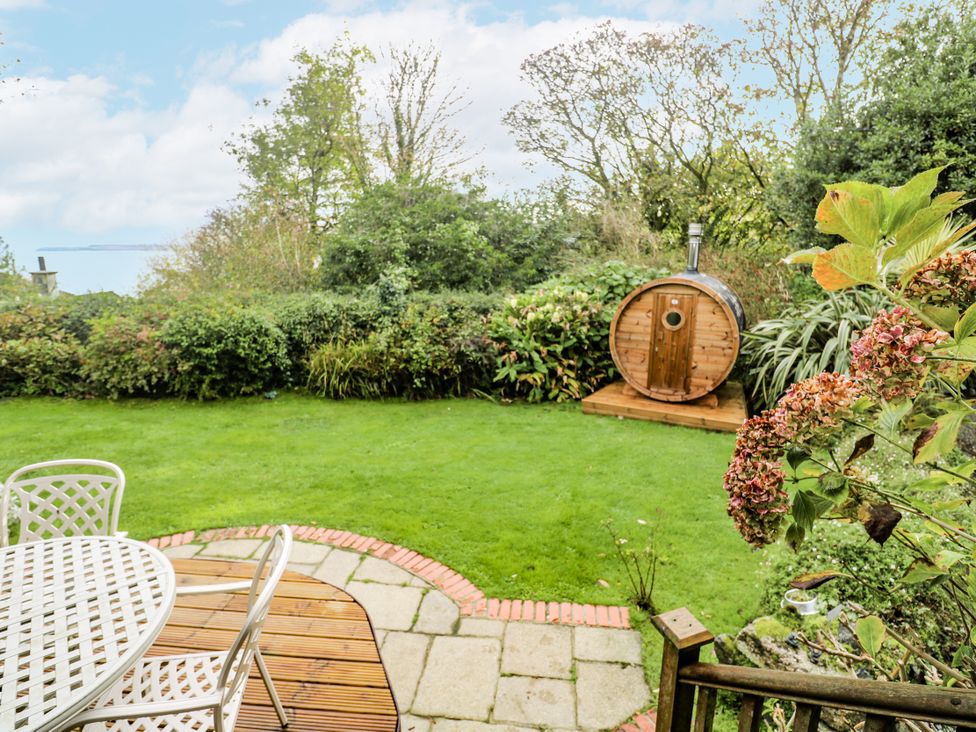 A garden with seating, a barrel sauna, and grass at Glenside House in Carbis Bay