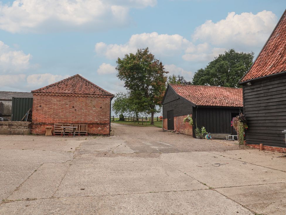An outdoor area with buildings and a tree at The Cow Shed in Chediston near Halesworth