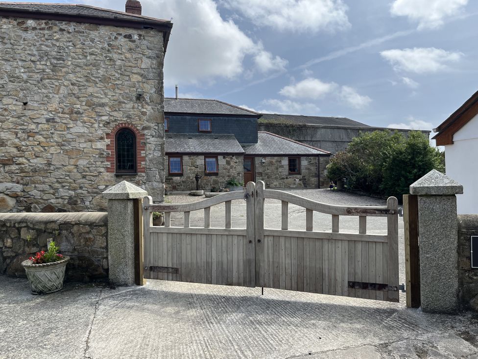 A stone building with a wooden gate and gravel driveway at Riviere House Hayle