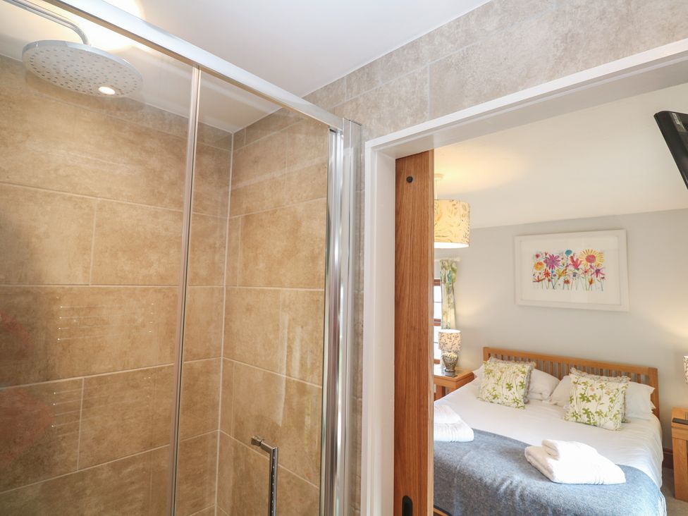 A bathroom with a shower and a bed visible at Riviere House in Hayle