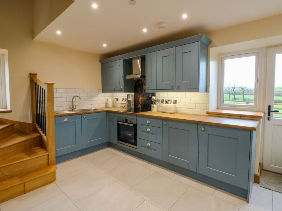 A kitchen with blue cabinets and a wooden countertop at Y Stabal near Llanilar