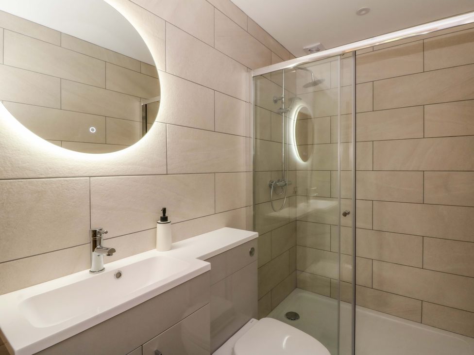 A bathroom with a sink, shower, and mirror at Y Stabal near Llanilar