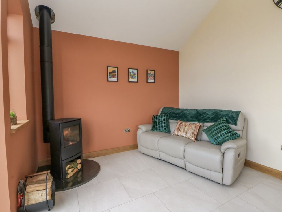 A living room with a sofa and a wood stove at Y Stabal near Llanilar