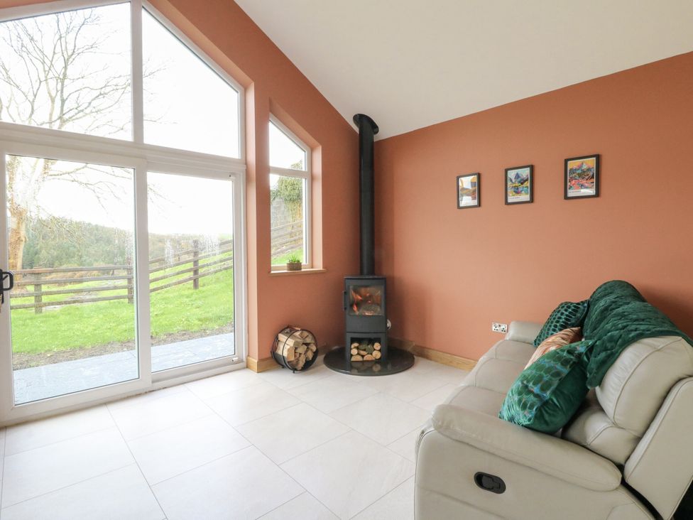 A snug with a stove and a sofa at Y Stabal near Llanilar