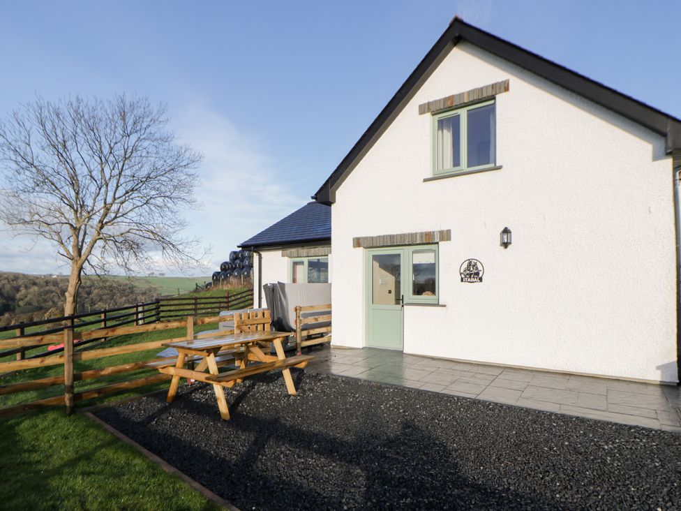 A house exterior with a table and benches at Y Stabal near Llanilar