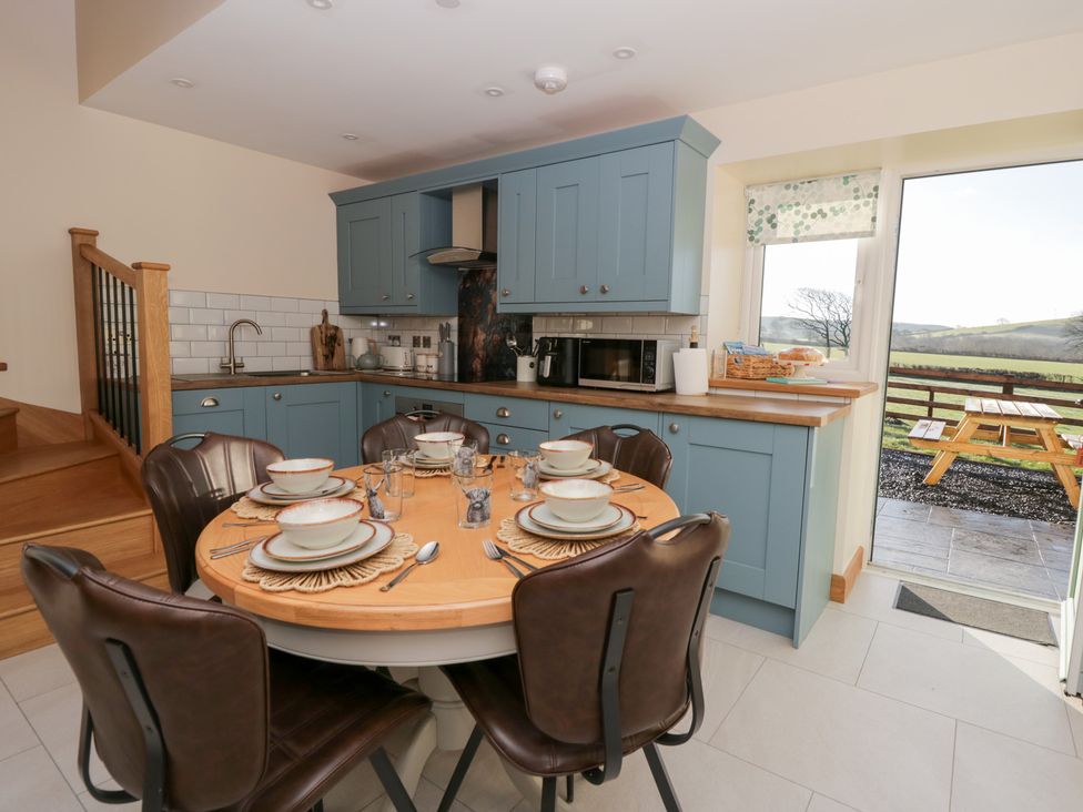 A kitchen with a dining table set for a meal at Y Stabal near Llanilar