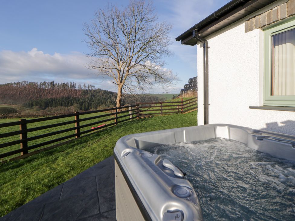 A hot tub with a view of a fence and tree at Y Stabal near Llanilar