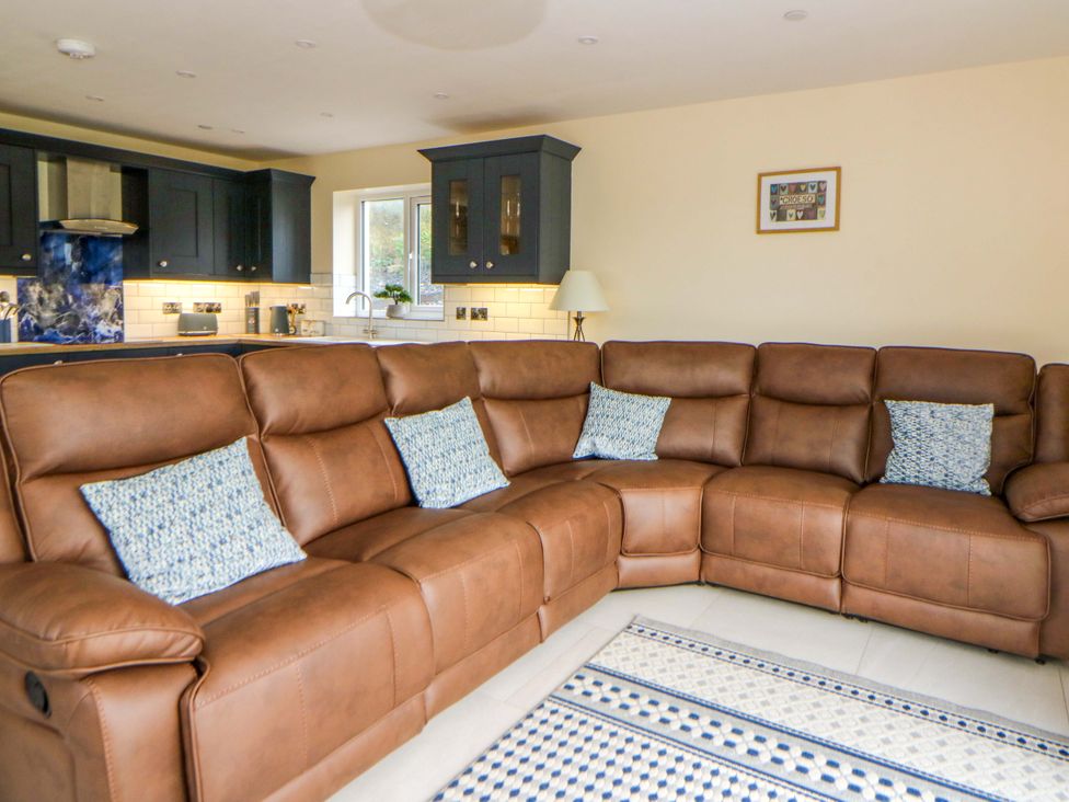 A living room with a sofa and kitchen visible at Y Beudy near Llanilar