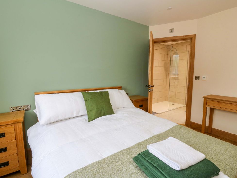 A bedroom with a bed and an ensuite shower at Y Beudy near Llanilar
