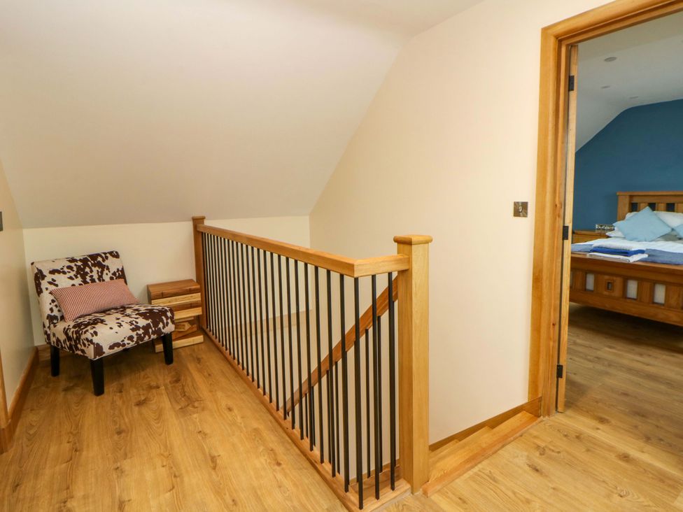 An upstairs hallway with a chair and staircase at Y Beudy near Llanilar