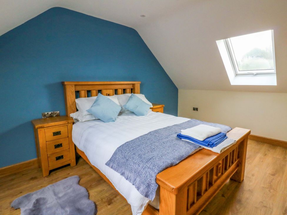 A bedroom with a wooden bed and bedside table at Y Beudy near Llanilar