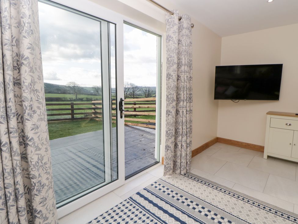 A living room with a sliding door and television at Beudy near Llanilar