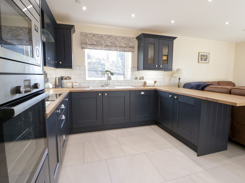 A kitchen with cabinets and a counter near a window at Beudy near Llanilar