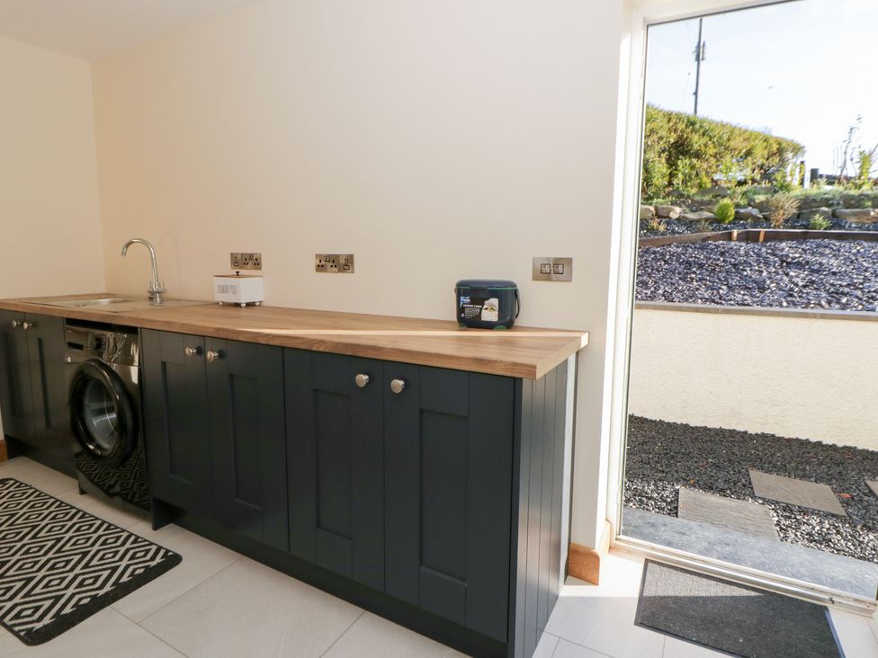 A utility room with a washing machine and sink at Beudy near Llanilar