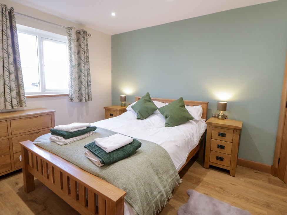 A bedroom with a bed and dresser at Beudy near Llanilar