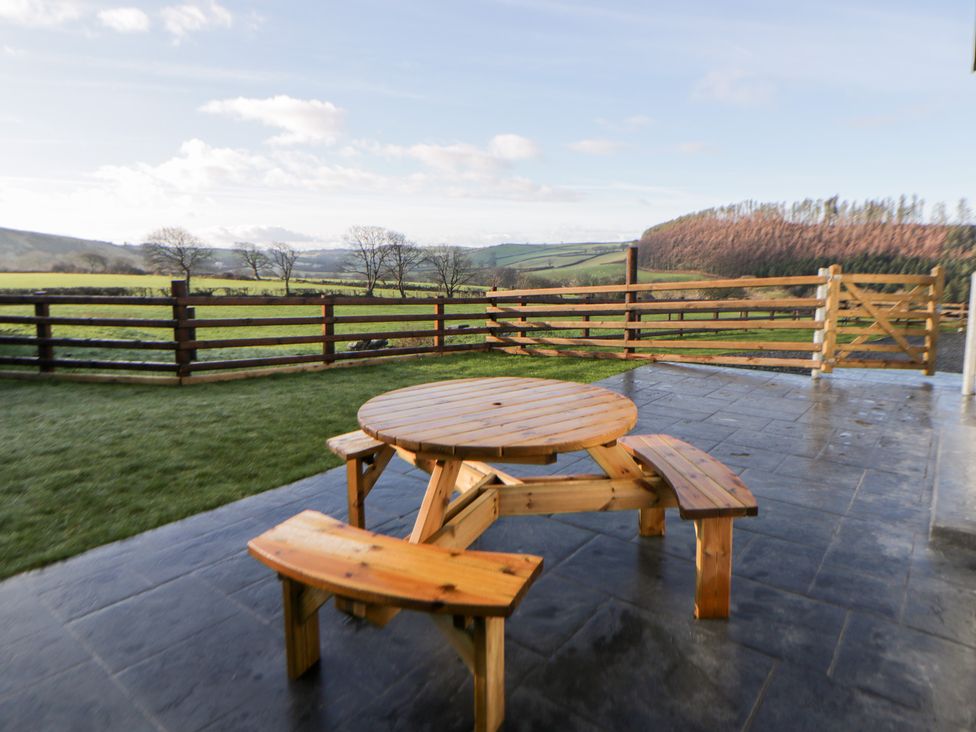 An outdoor area with a wooden table and benches at Beudy near Llanilar