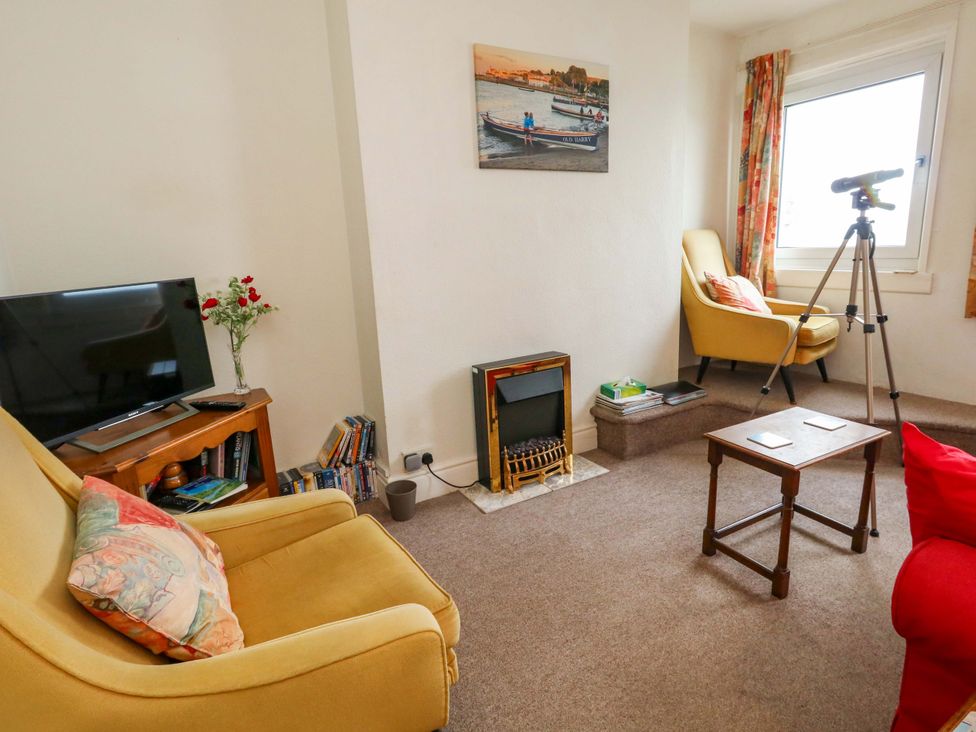 A living room with a television and armchairs at Bay View in Swanage
