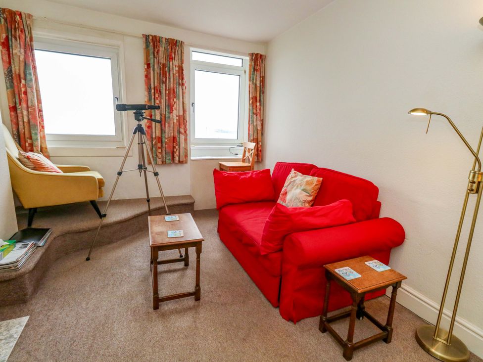 A living room with a red sofa and an armchair at Bay View in Swanage