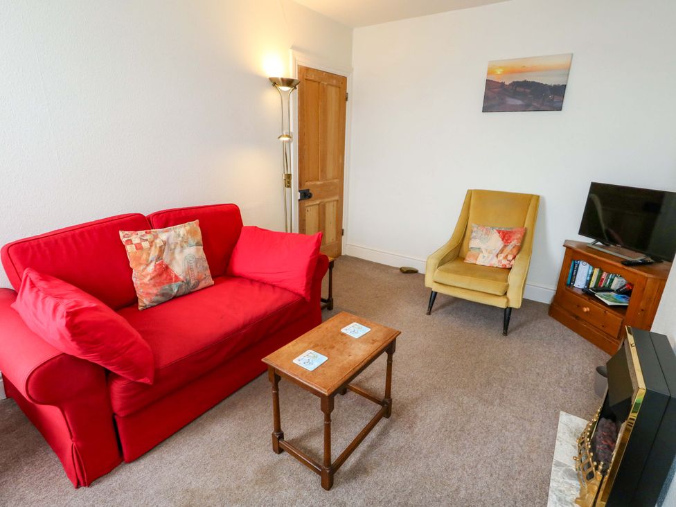 A living room with a red sofa, armchair, and coffee table at Bay View in Swanage