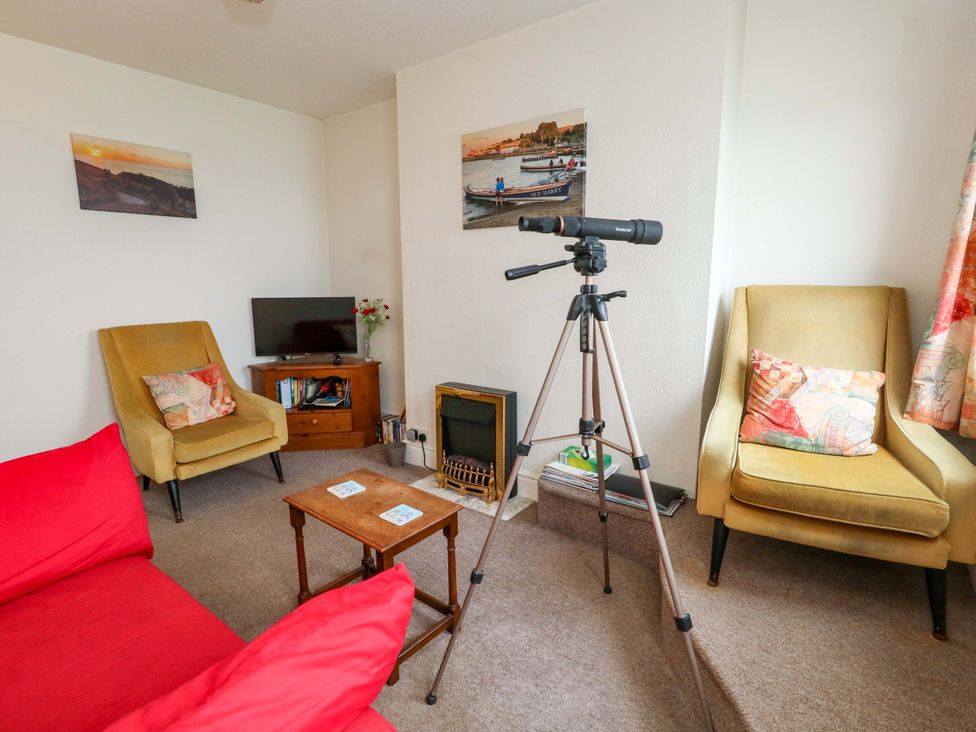 A living room with a telescope and seating at Bay View in Swanage