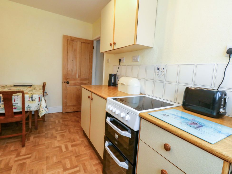 A kitchen with an oven, stove, table, and toaster at Bay View in Swanage
