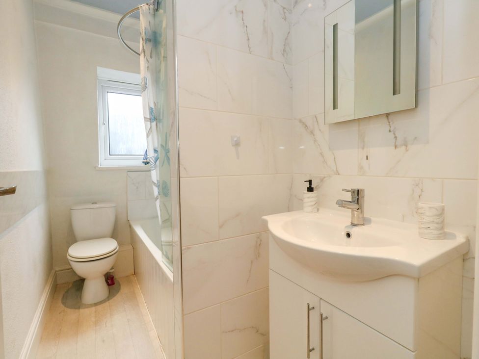 A bathroom with a toilet, sink, bathtub, and window at Bay View in Swanage