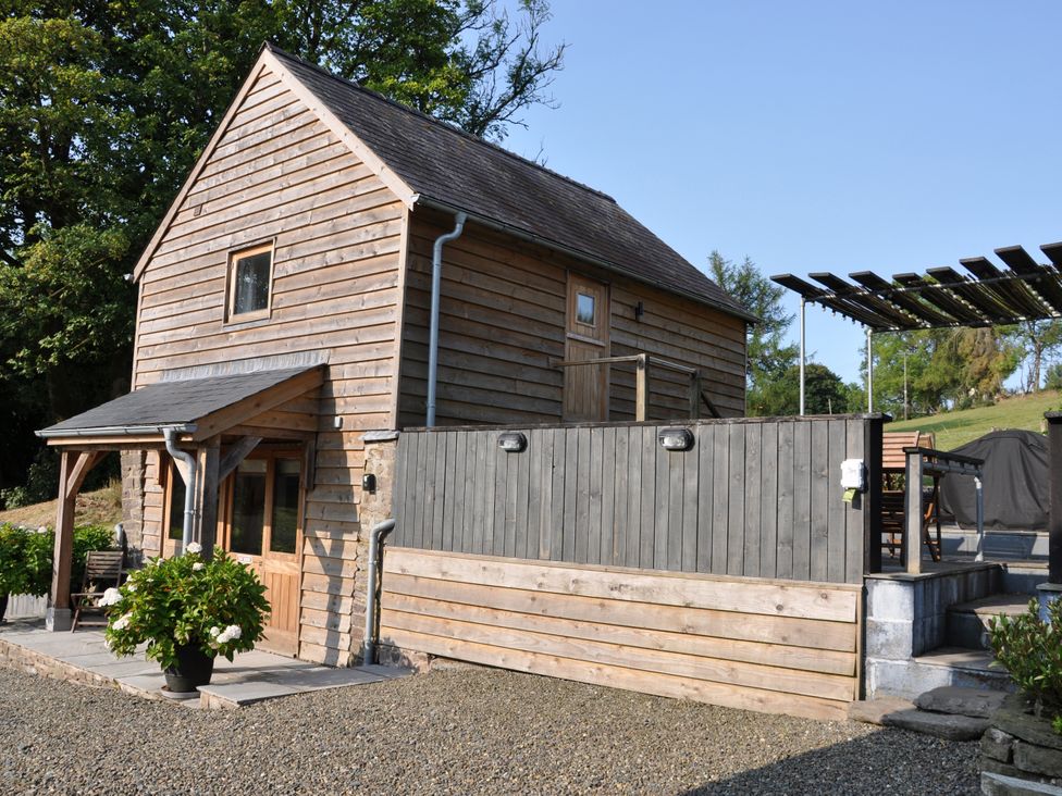 A wooden house with a patio and outdoor furniture at Rockhill Farm Hay Barn in Clun