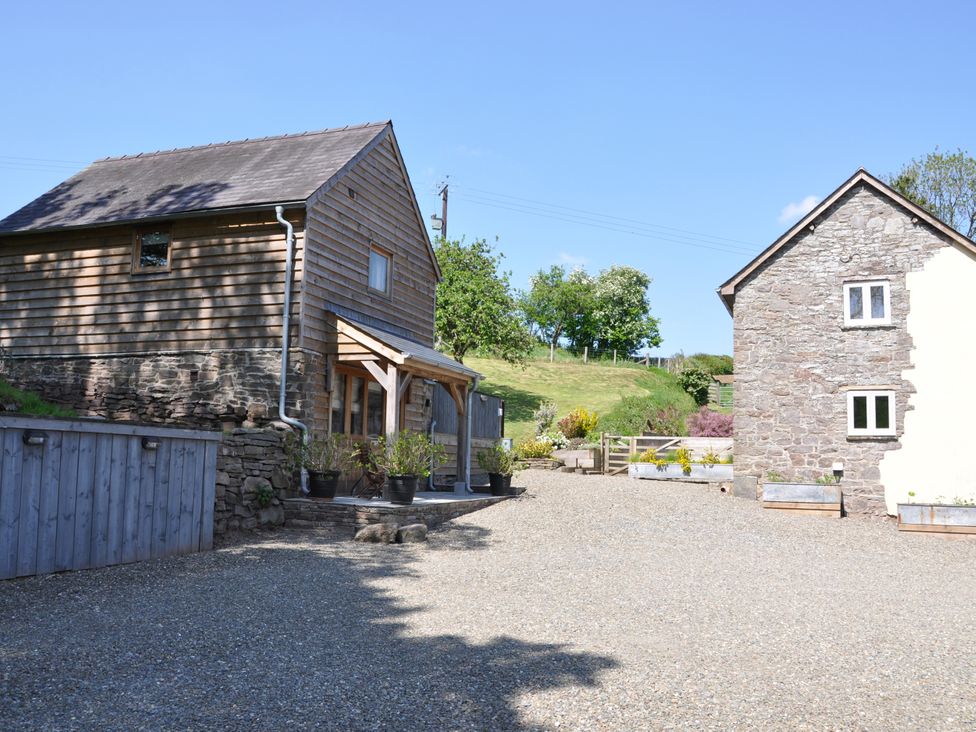 An outdoor view of two houses with a gravel driveway at Rockhill Farm Hay Barn in Clun