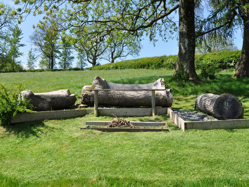 An outdoor area with logs and a fire pit at Rockhill Farm Hay Barn Clun