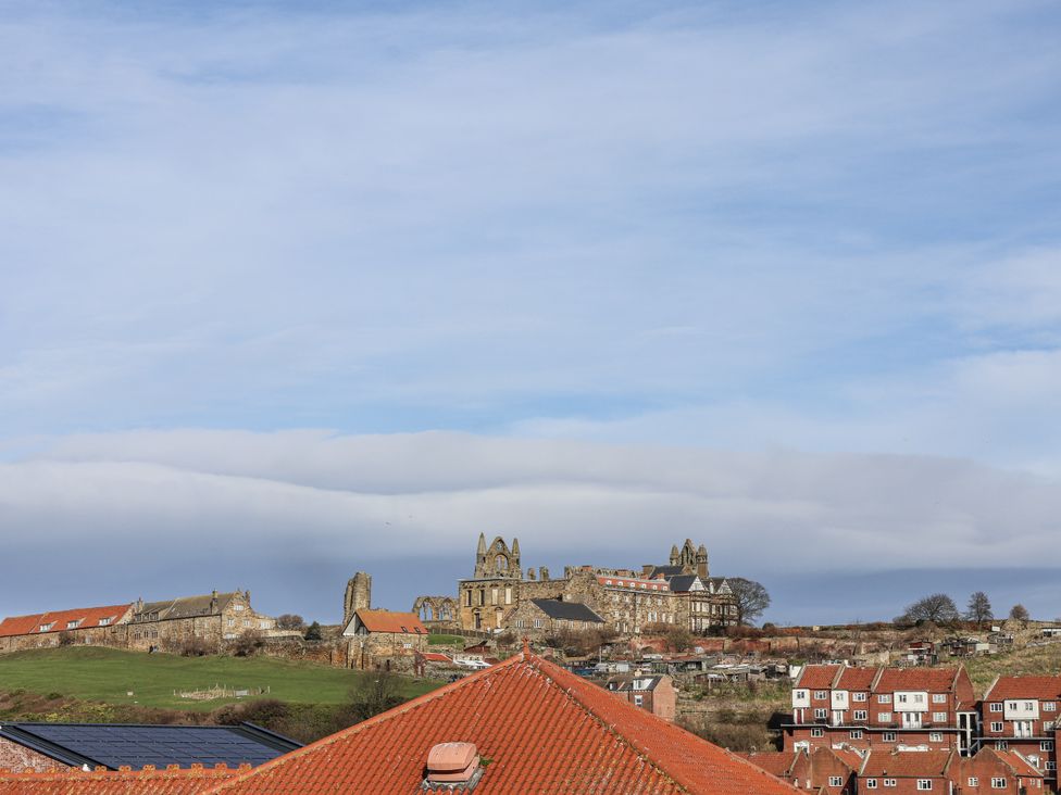 A view of rooftops and buildings with hills and clouds at Whitby View in Whitby