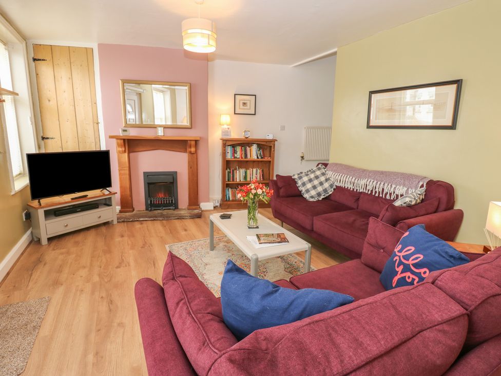 A living room with a television and a bookshelf at 1 Eden Cottages, Corby Hill