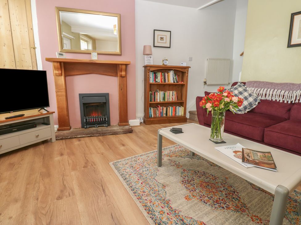A living room with a fireplace and bookshelf at 1 Eden Cottages Corby Hill