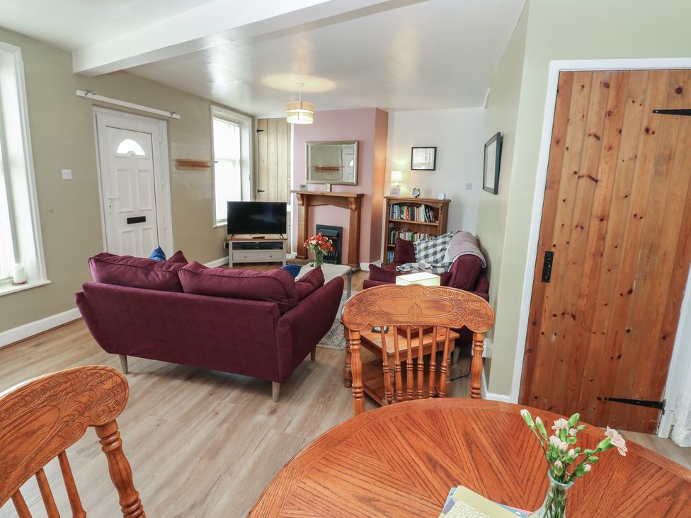 A living room with a sofa and television at 1 Eden Cottages in Corby Hill
