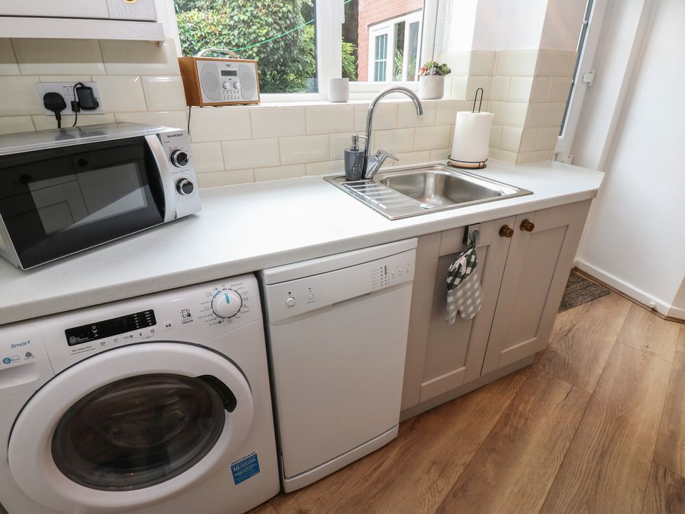 A kitchen with appliances including a washing machine and microwave at 1 Eden Cottages Corby Hill