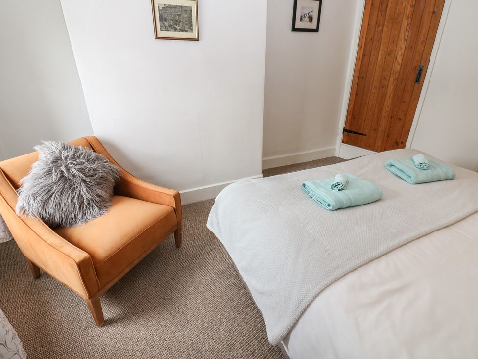 A bedroom with a chair and towels on the bed at 1 Eden Cottages in Corby Hill