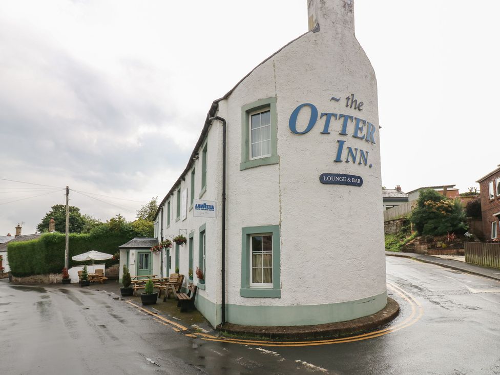 A building with a sign for the Otter Inn and outdoor seating at 1 Eden Cottages in Corby Hill
