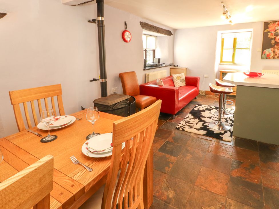 A kitchen with dining area, stove and sofa at Beck Edge in Braithwaite