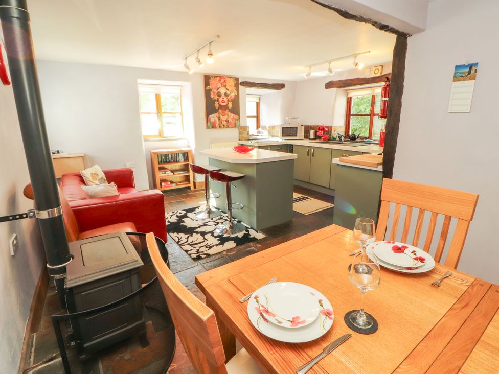 A kitchen and dining area with a stove and seating at Beck Edge in Braithwaite