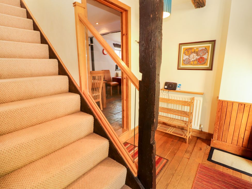 A hallway with stairs and wooden shelving at Beck Edge in Braithwaite